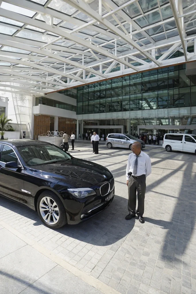 Professional chauffeur pickup under a hotel entrance canopy with luggage ready