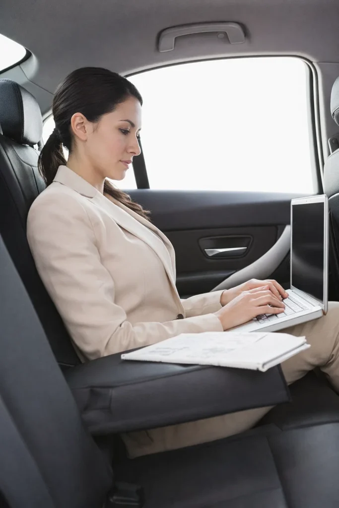 Executive sedan interior with passenger using a laptop during a quiet ride
