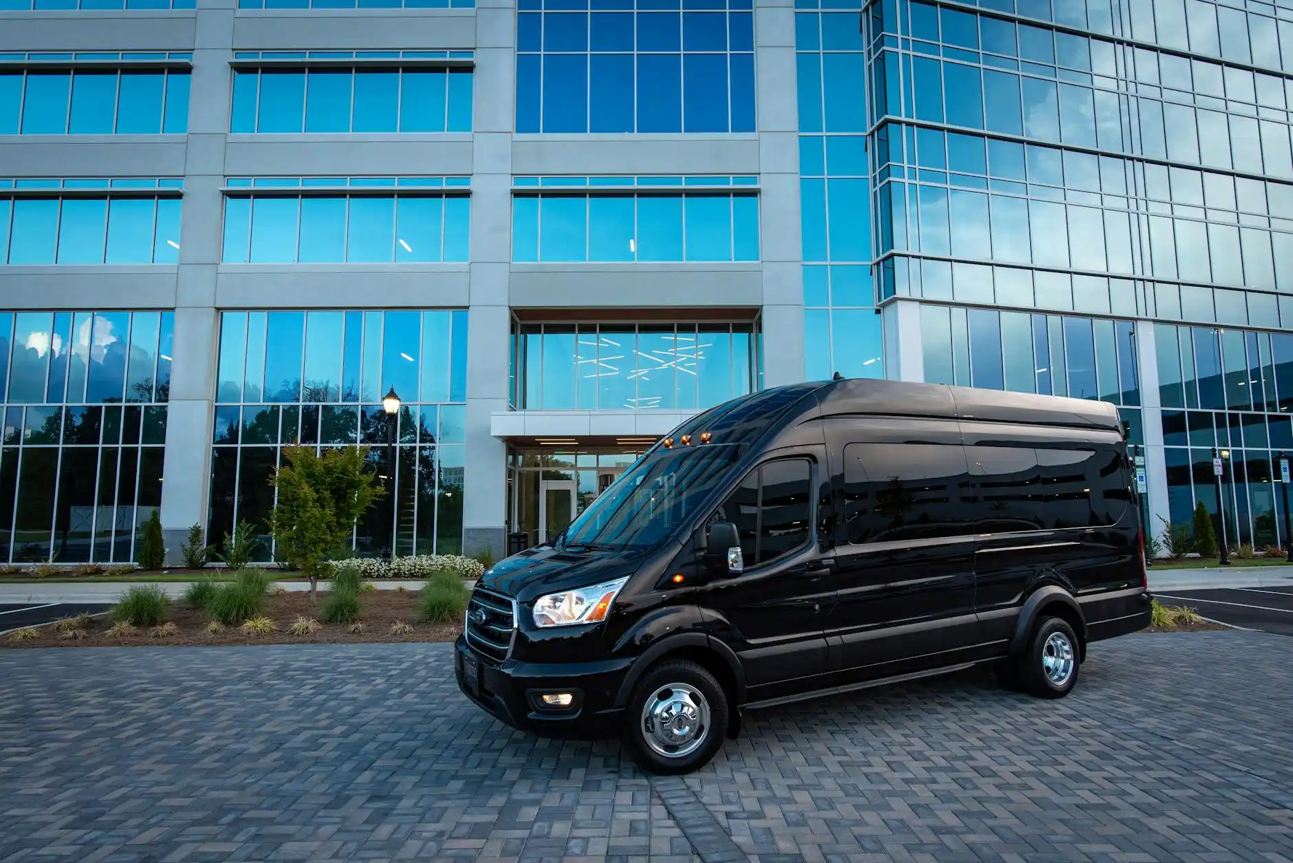 lineup of luxury transportation vehicles including executive sedan, black SUV, stretch limousine, sprinter van, and mini coach in a polished Seattle hotel driveway