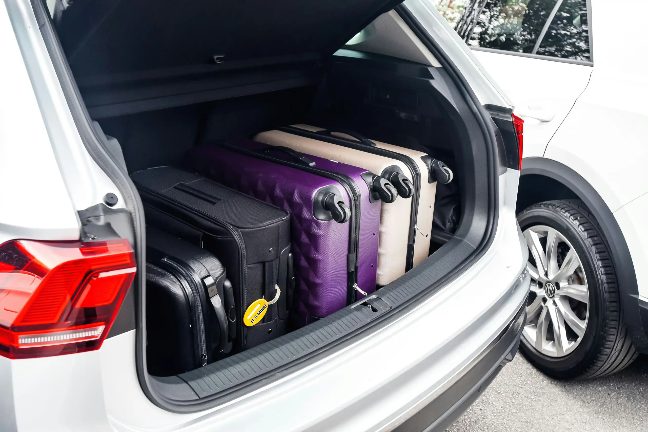 airport curbside scene at Seattle-Tacoma International Airport with chauffeur loading multiple suitcases into a luxury SUV while travelers stand nearby