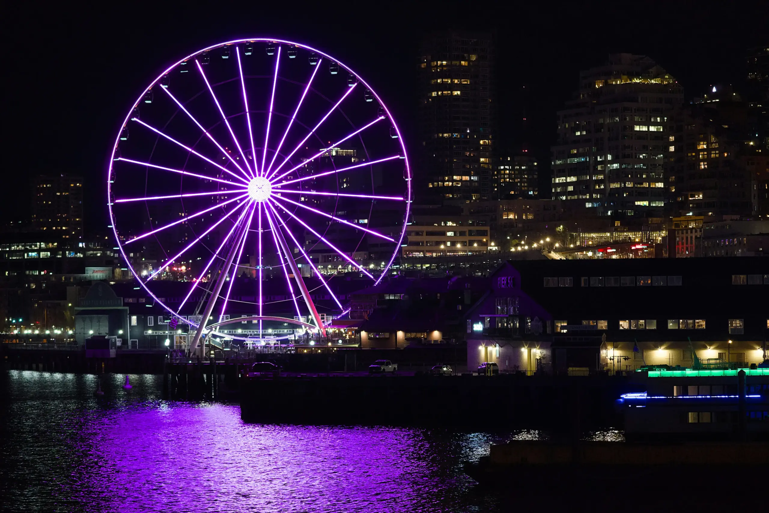 glossy black stretch limousine parked at sunset near Seattle waterfront with ferris wheel, glowing city lights, and well-dressed passengers stepping out