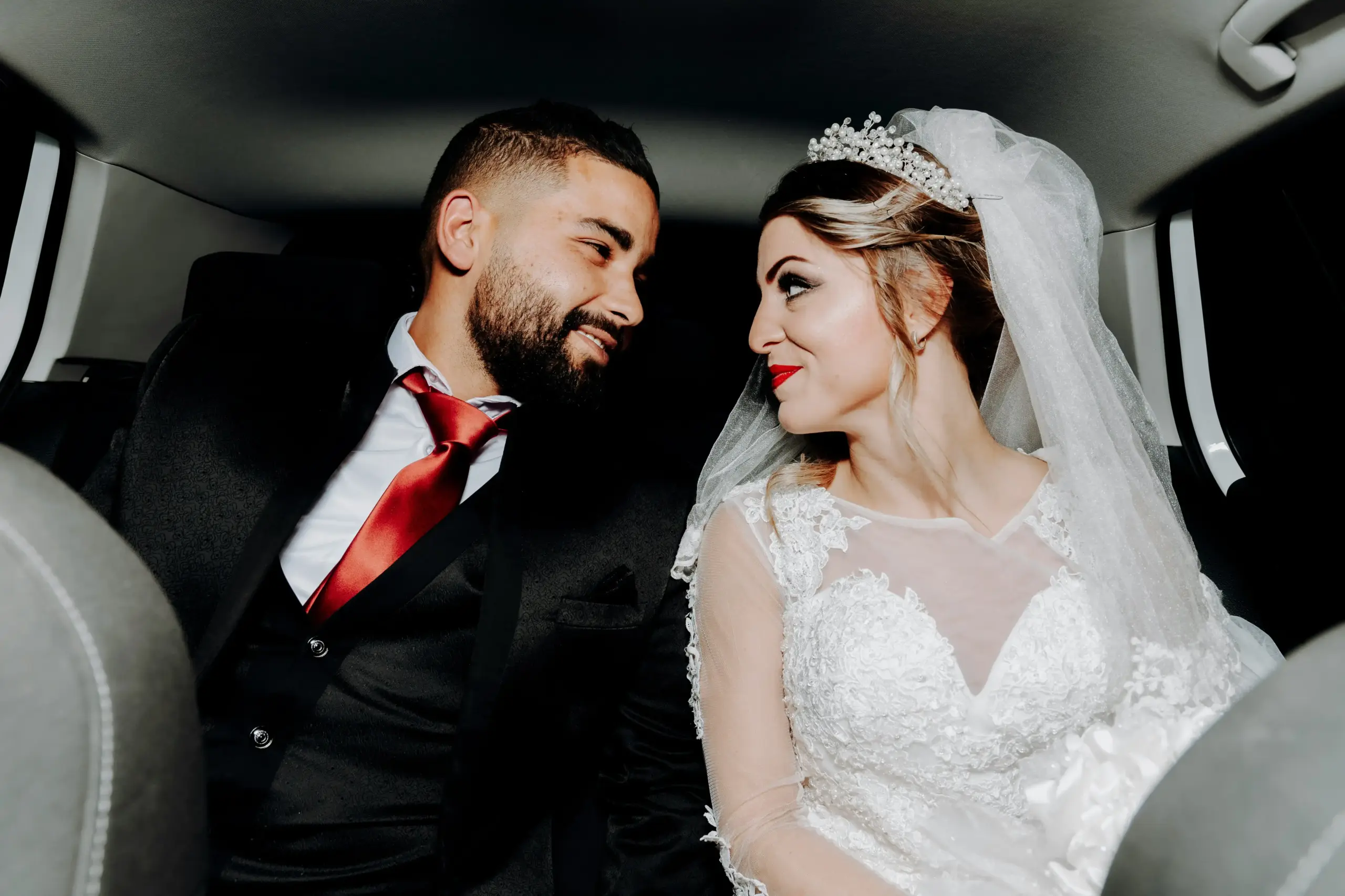 bride and groom seated in a luxury black limousine interior with cream leather seats, city lights of downtown Seattle reflecting through windows, candid joyful moment