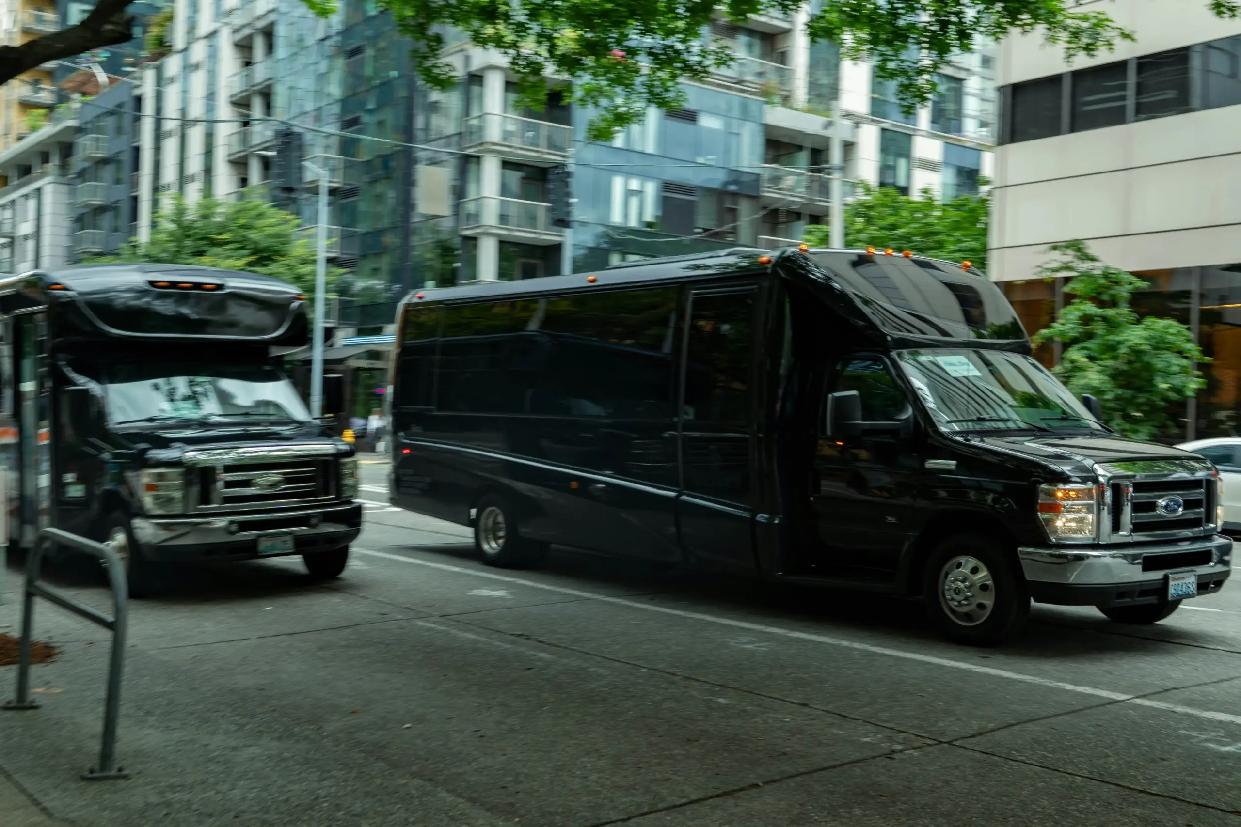 nighttime airport pickup lane at Sea-Tac with sleek black limousine under terminal lights, chauffeur in dark overcoat greeting arriving passenger, rain-slick pavement reflecting...