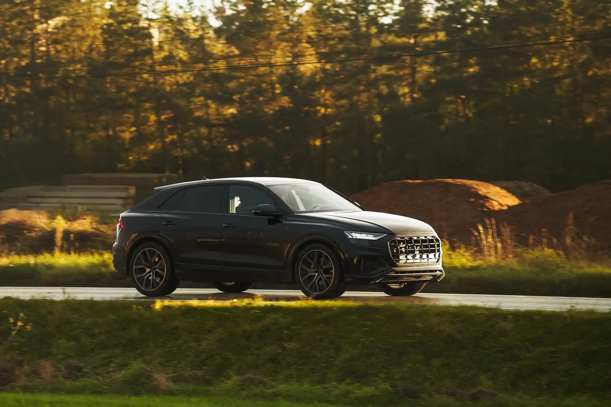 glossy black luxury SUV parked outside an upscale Seattle golf club at sunrise, golf bags neatly loaded in rear cargo area, evergreen trees and misty Pacific Northwest light