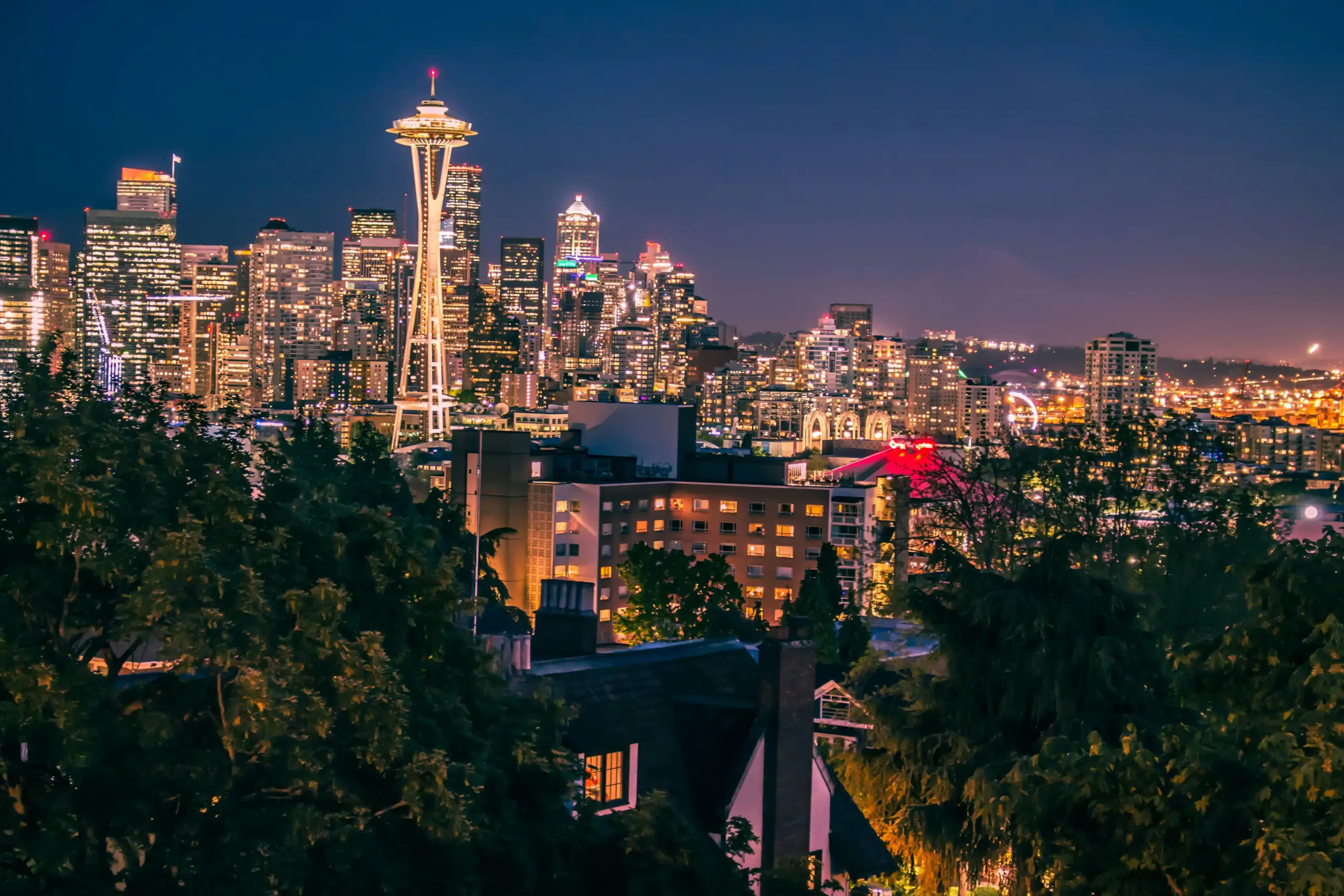 overhead aerial view of Seattle stadium district during a Mariners game, dense traffic patterns, illuminated streets, T-Mobile Park crowded with fans, luxury SUV navigating desi...