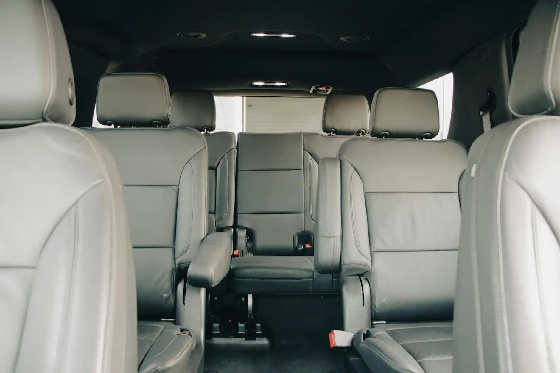 detailed interior of a luxury black SUV with tan leather seats, folded third row, four golf bags and travel luggage arranged neatly, Seattle skyline faintly visible through windows