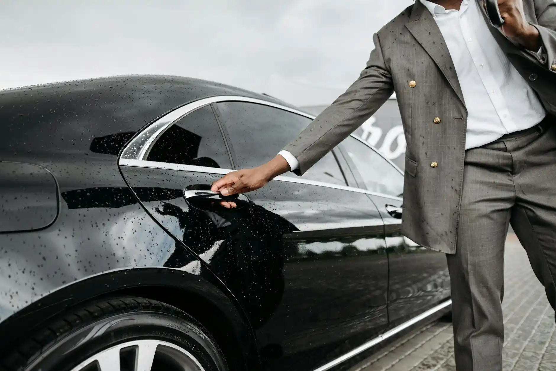 nighttime Seattle streets after a Mariners game, crowds dispersing from T-Mobile Park while a chauffeur opens the door of a sleek black sedan for passengers near a designated pi...