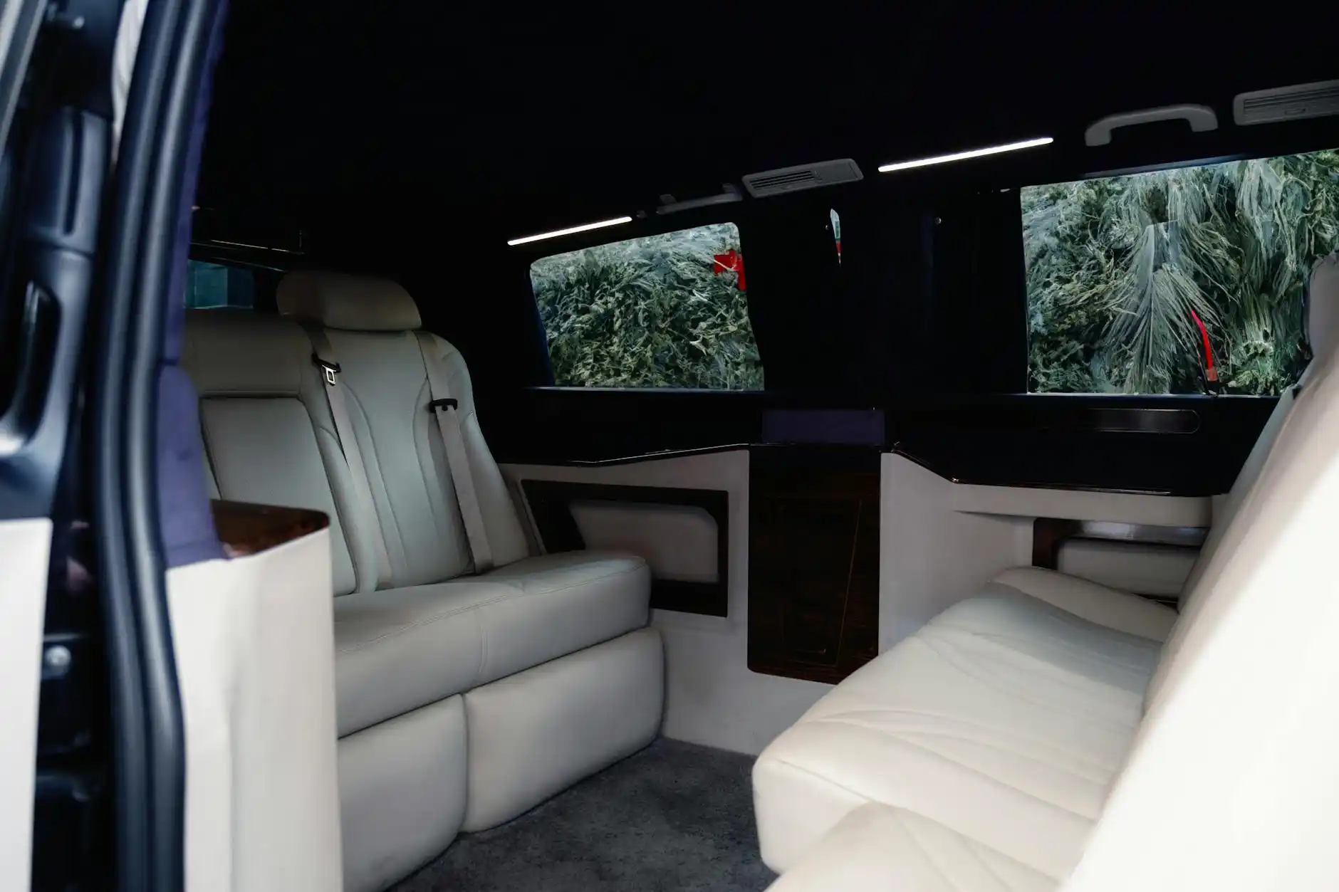 diverse corporate team inside a luxury sprinter van with leather seats and laptops, driving past Seattle waterfront and stadium district on an overcast afternoon