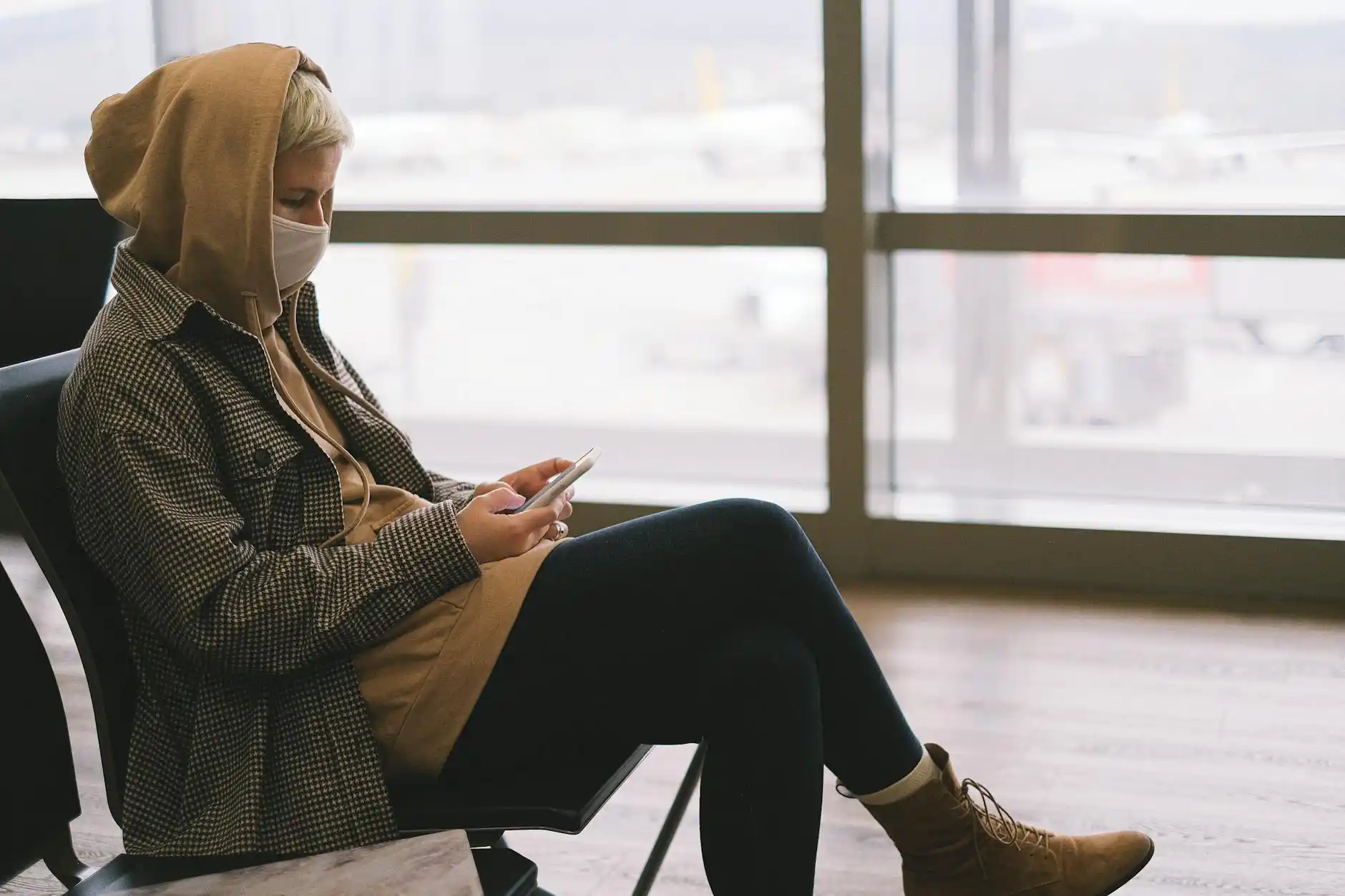 tired traveler stepping off escalator in Sea-Tac terminal looking relieved after seeing reserved driver information on smartphone, polished airport interior, carry-on luggage, c...