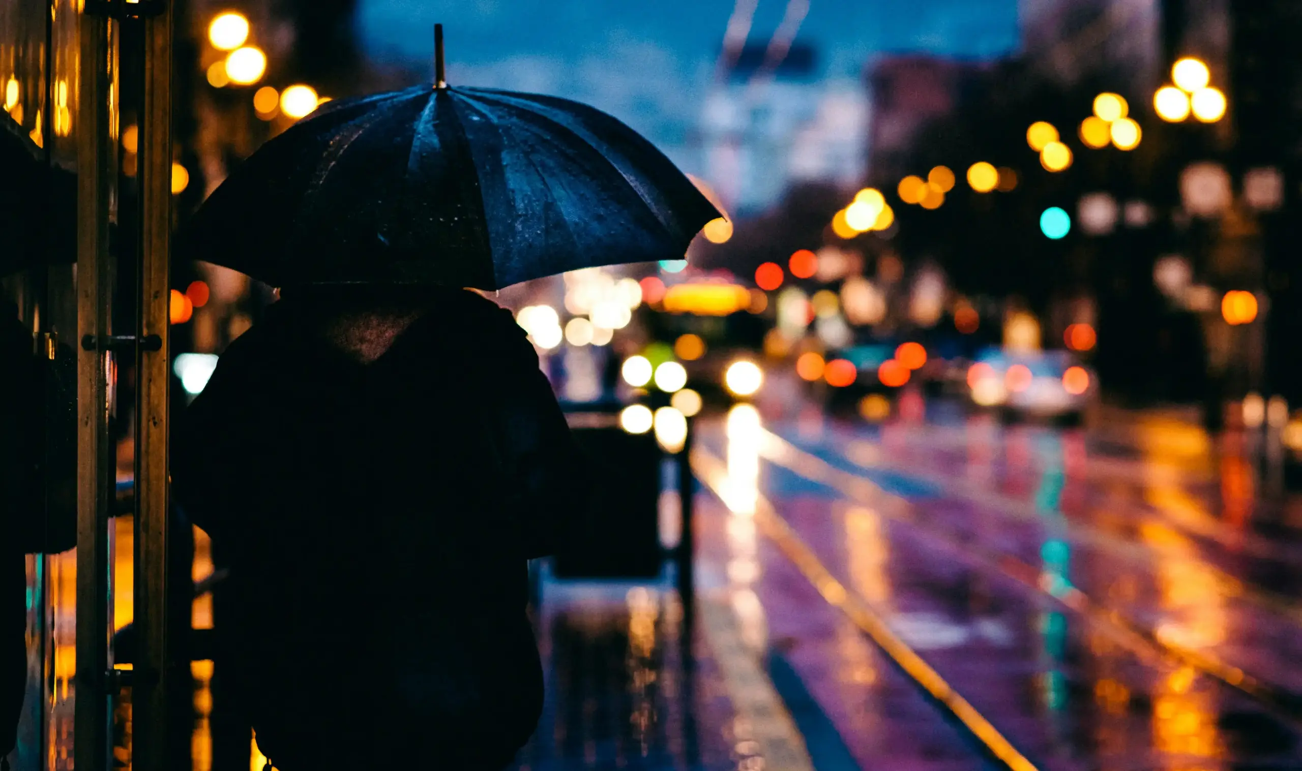 luxury black executive sedan parked in front of a modern downtown Seattle hotel entrance on a rainy evening, chauffeur holding umbrella, city lights reflecting on wet pavement