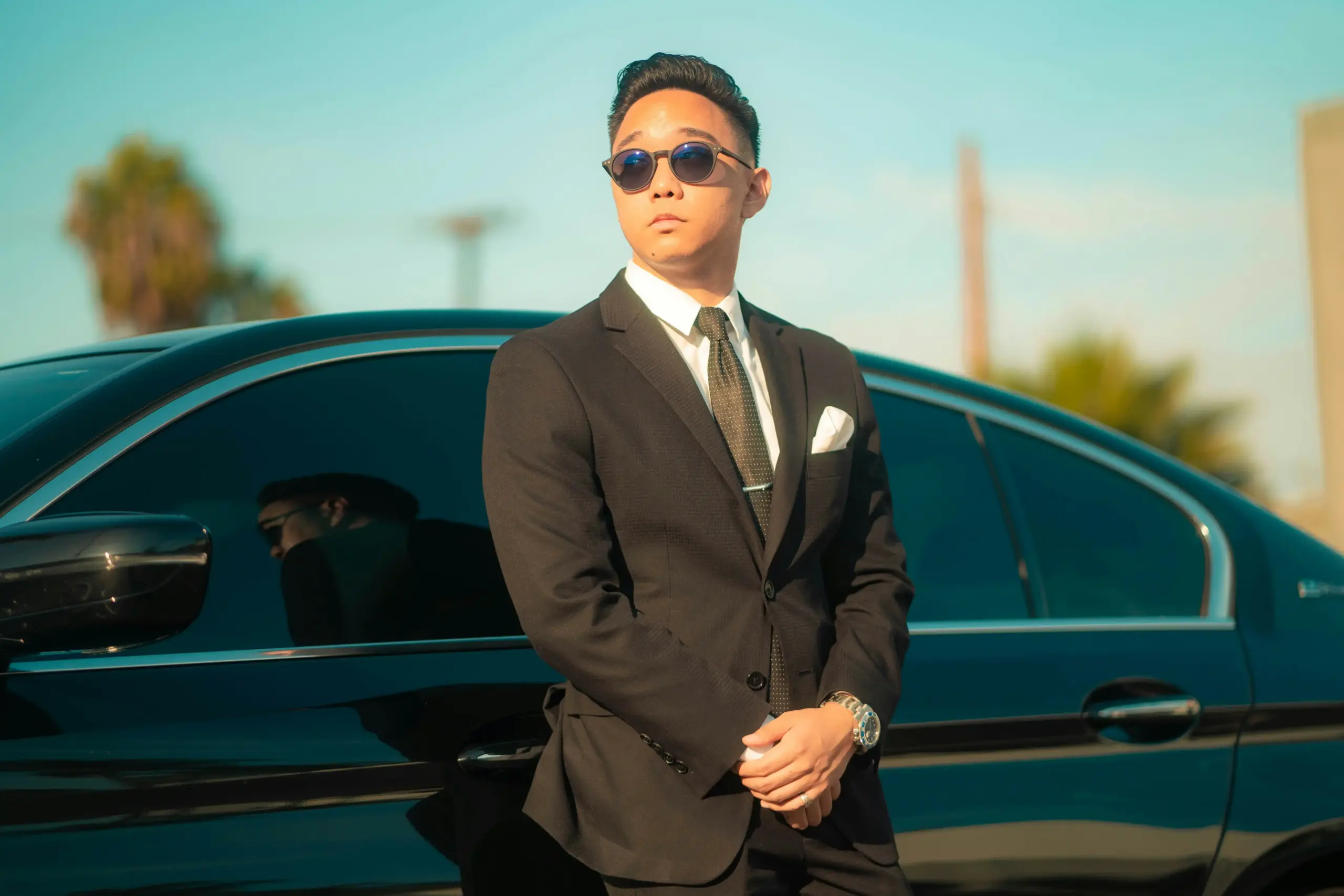 split-scene comparison showing an executive chauffeur assisting a business traveler with luggage beside a black sedan and a formal black stretch limousine outside a wedding venu...