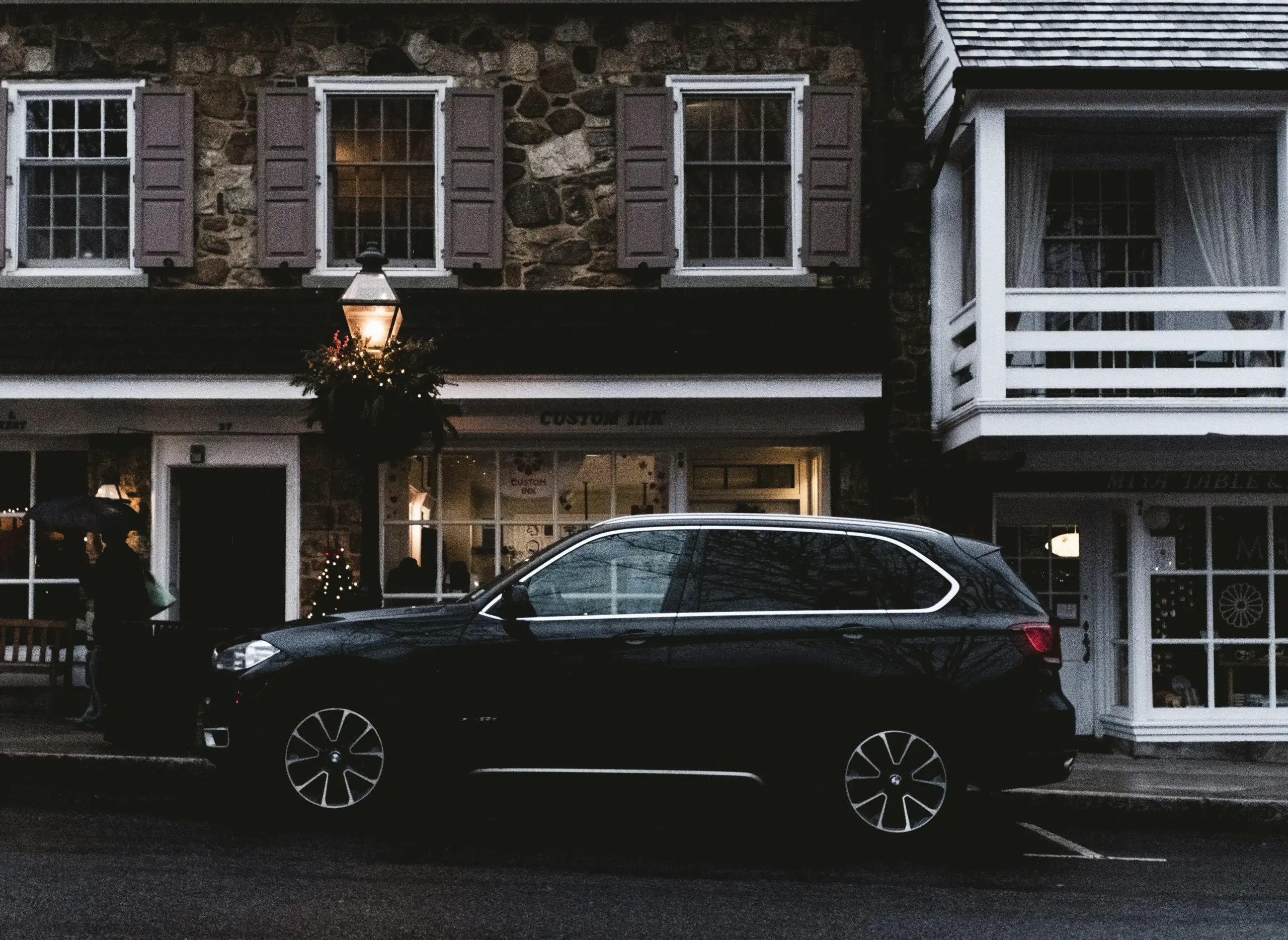 elegant black executive sedan and luxury SUV parked in front of a high-end Seattle hotel with glass facade, Space Needle faintly visible in distance, crisp evening lighting