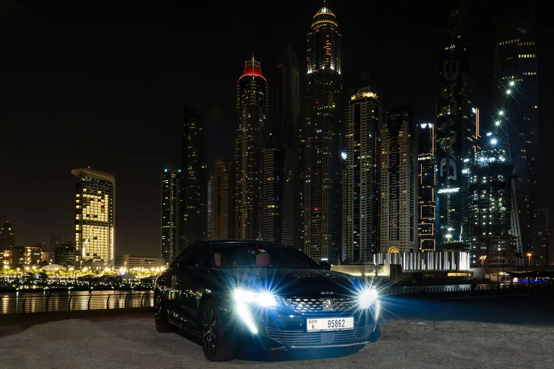 professional chauffeur opening rear door of sleek black sedan for business traveler outside a modern Seattle hotel at night, city skyline and soft streetlights in background