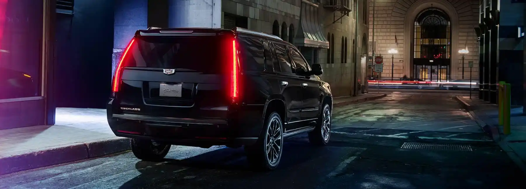 black luxury sedan parked curbside at a modern airport terminal at dusk, chauffeur in dark suit opening rear door, warm city lights reflecting on glossy paint