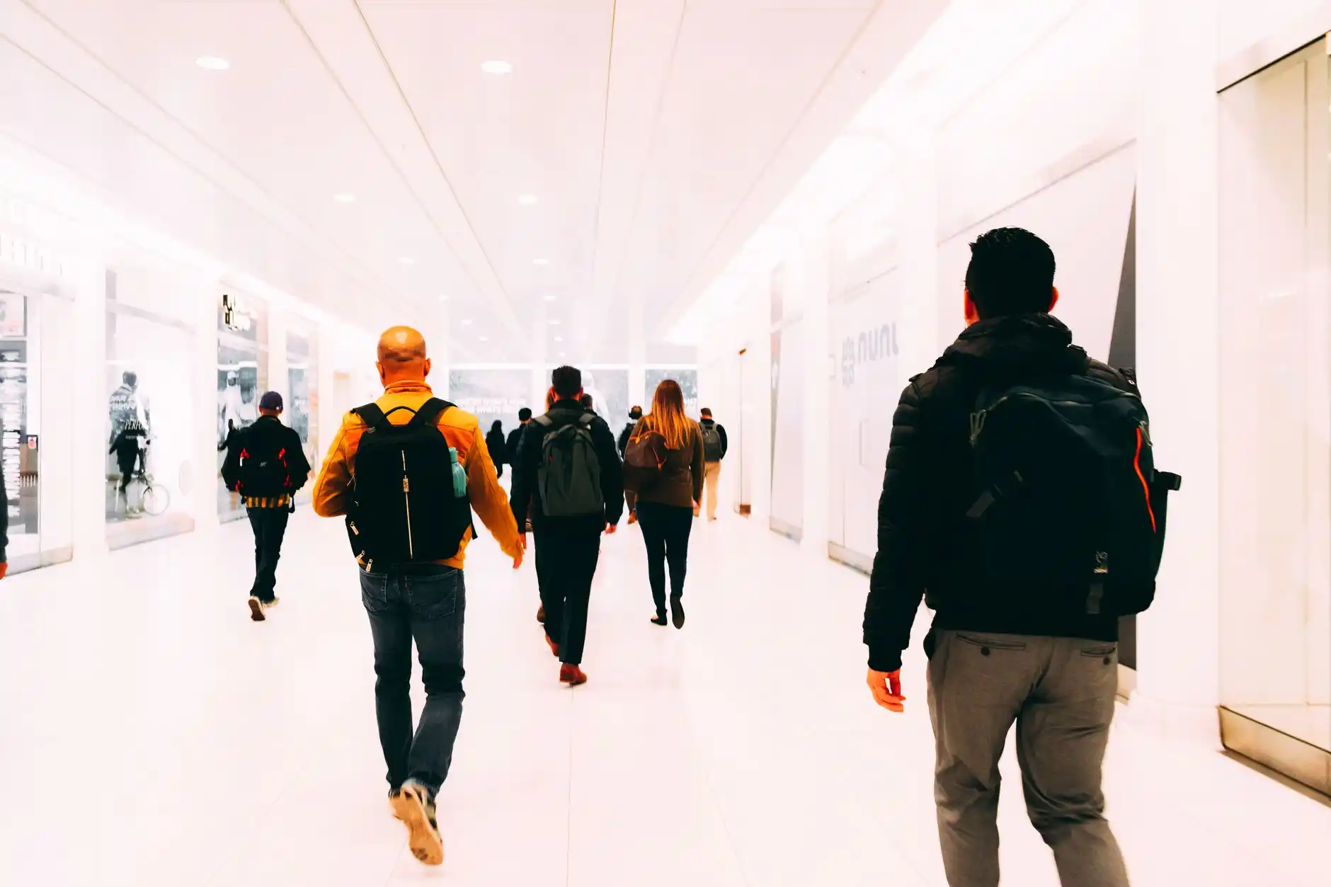 interior of SeaTac Airport main terminal with travelers rolling luggage, overhead flight boards, bright natural light, and directional signs to baggage claim and ground transpor...
