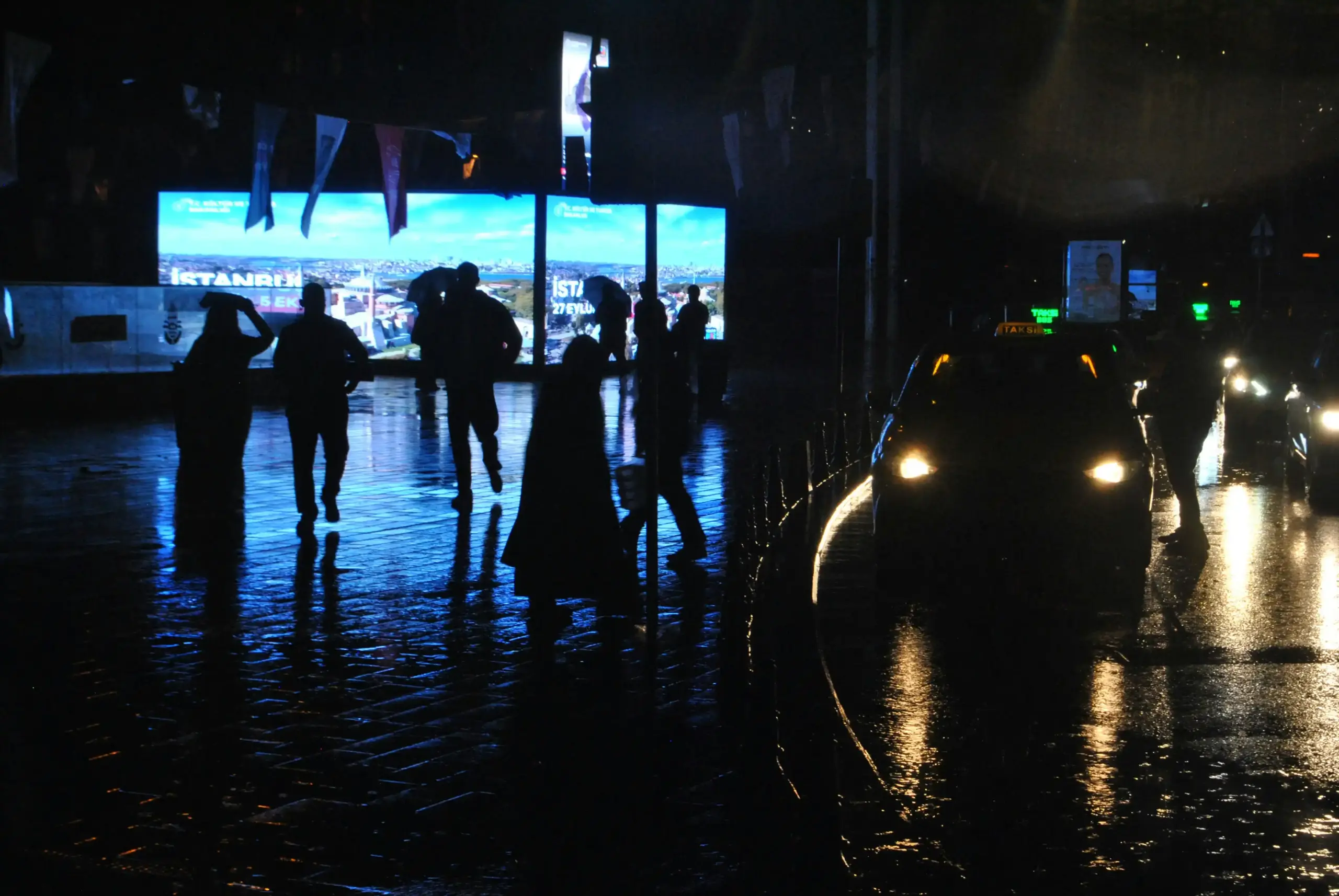 sleek black luxury sedan and full-size SUV parked outside a modern glass hotel entrance in downtown Seattle at dusk, valet staff nearby, wet pavement reflecting city lights