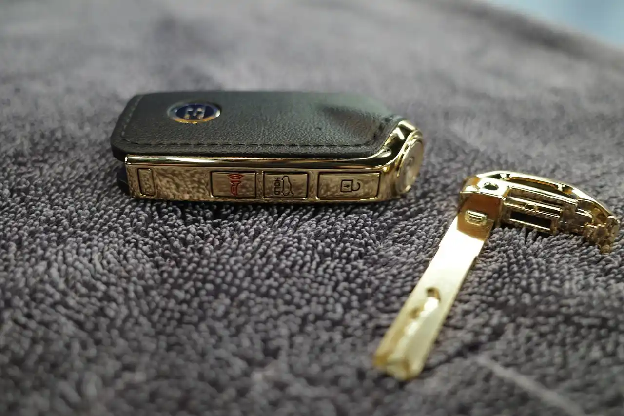 smartphone showing a car service booking confirmation email next to a printed itinerary, car keys, and a wristwatch on a clean desk