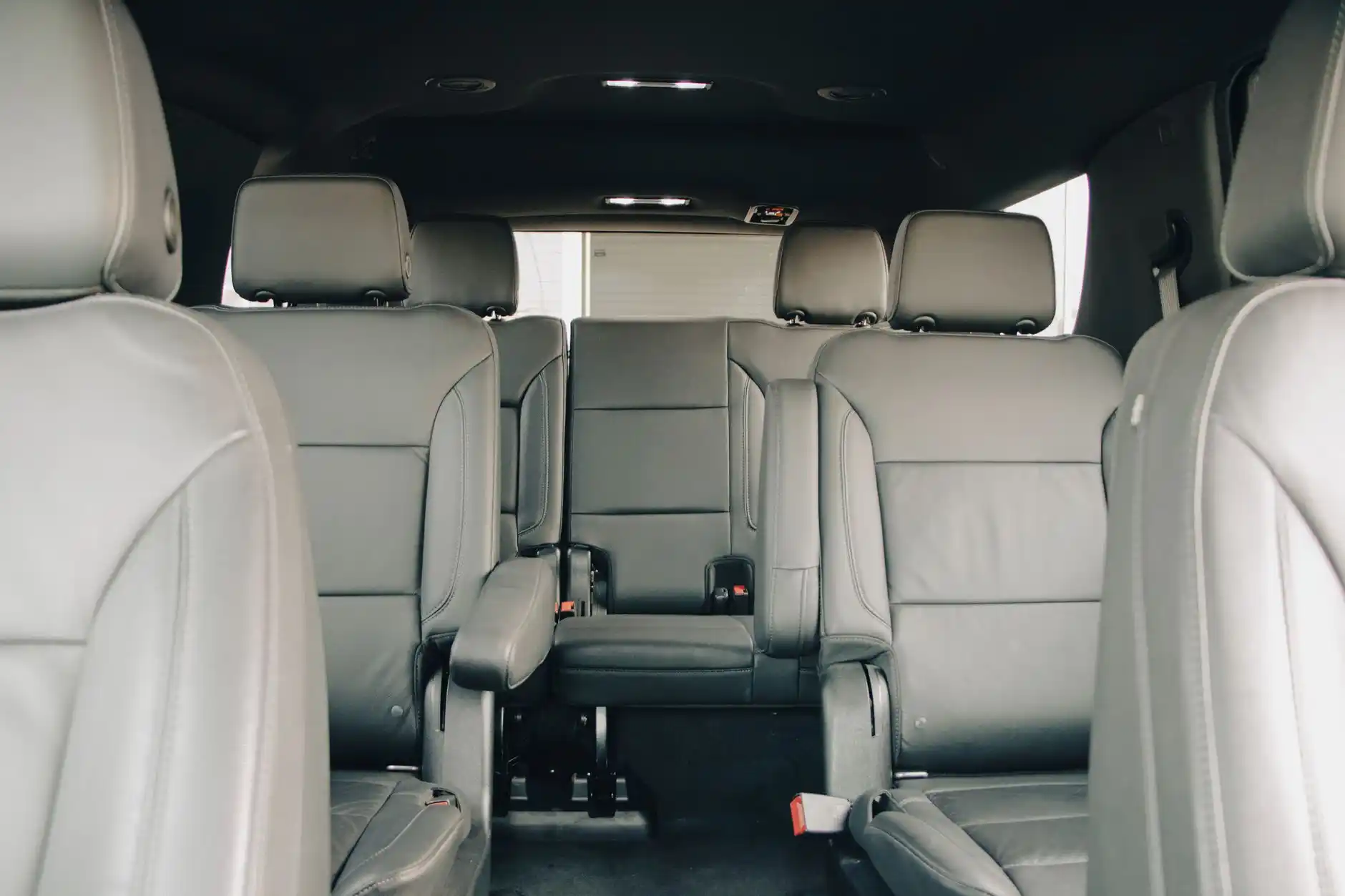 detailed interior of a luxury black SUV with leather seats, bottled water, soft ambient lighting, and Seattle skyline visible through rain-speckled windows